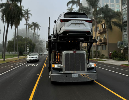 Front view of a fully loaded 9-car open hauler in the city, providing efficient door-to-door car shipping services