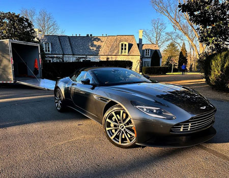 Aston Martin delivered in a residential yard using an enclosed trailer, showcasing premium exotic car shipping services