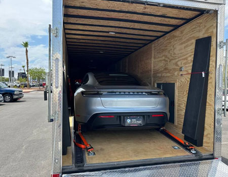 Porsche 911 securely strapped inside an enclosed trailer, representing professional exotic auto transport services