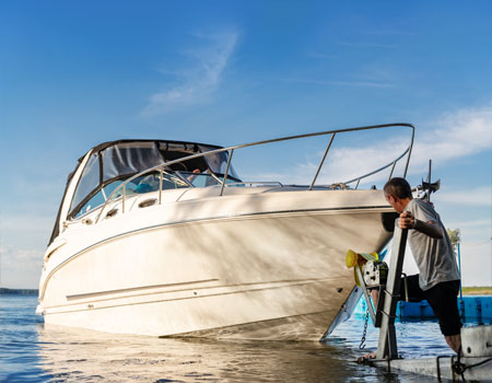 Luxury cabin motorboat being launched into the water from a trailer ramp with assistance, showing careful handling during boat transport services