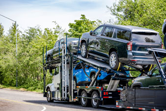 Classic open car carrier truck transporting pickup trucks and SUVs, providing reliable door-to-door car shipping service